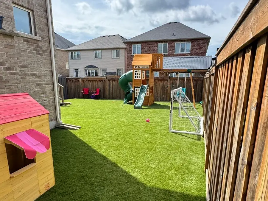 Artificial turf backyard with a play structure and dog house