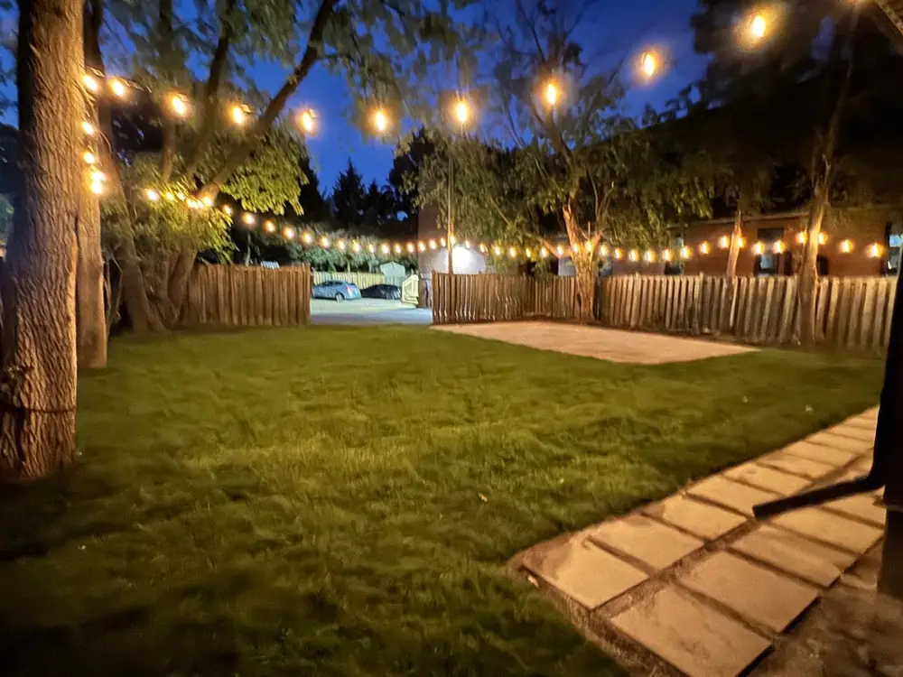 Finished backyard at dusk with string lights over the patio