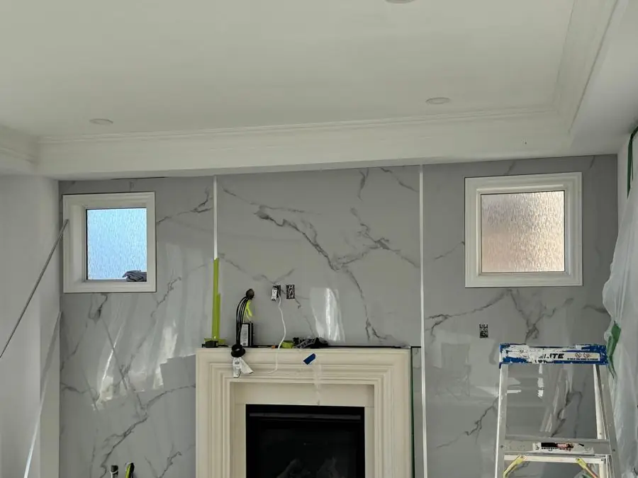 The same wall finished with a marble-look fireplace surround and mantel