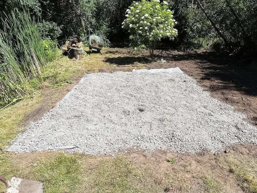 Compacted gravel pad laid over geotextile fabric on a lakeside site