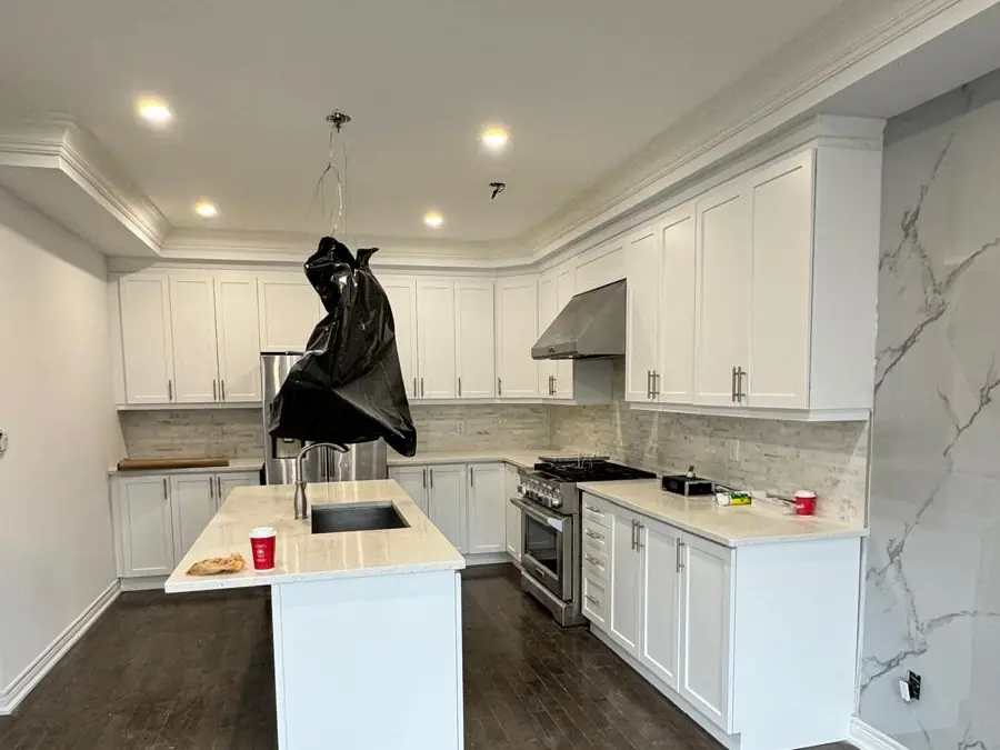 Kitchen finished in white after cabinet refinishing, with island and hardwood floor