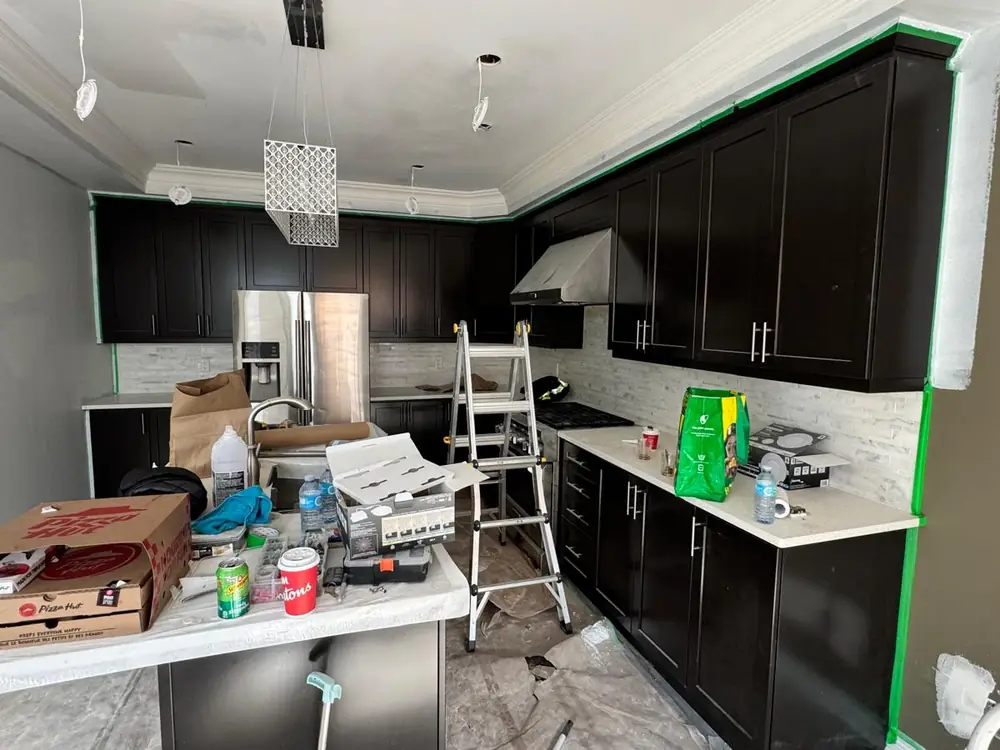 Kitchen with dark brown cabinets masked off part-way through refinishing