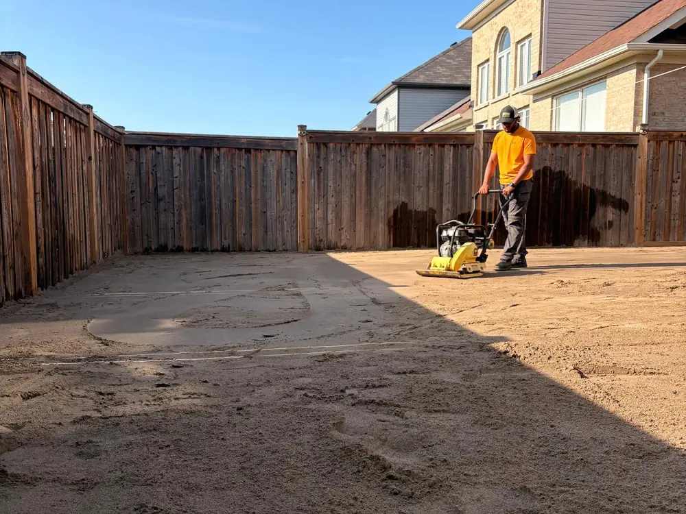 Crew member running a plate compactor across the bedding course