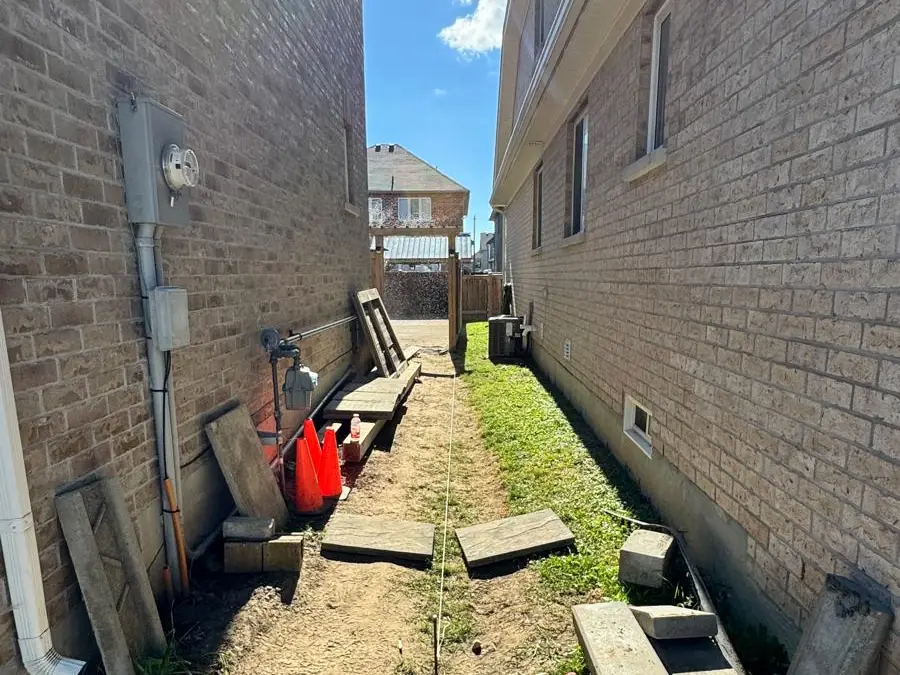 Narrow side yard with patchy grass and construction debris before work started